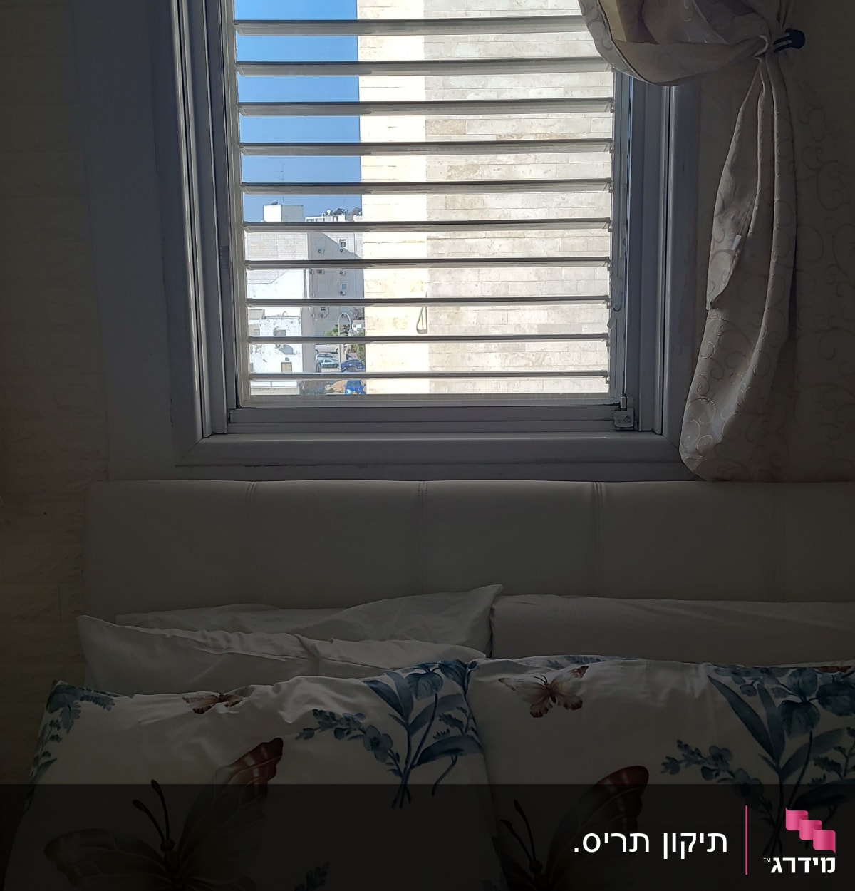 תריסים לבנים פתוחים בחלון עם וילון בצד